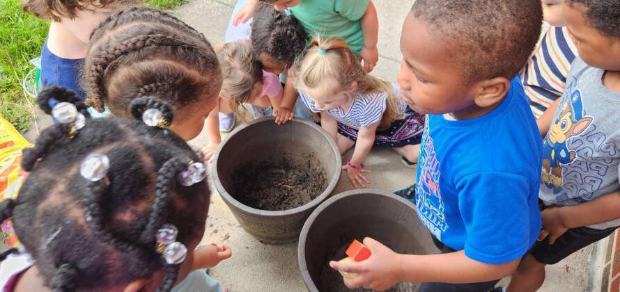 children standing around two planters of dirt